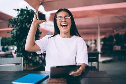 A woman celebrates as she wins a social media contest due to ticket giveaway ideas from a company.